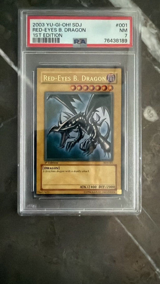 A graded Yu-Gi-Oh! trading card of Red-Eyes B. Dragon, PSA 7, sealed in a clear plastic protective slab on a dark marble surface.