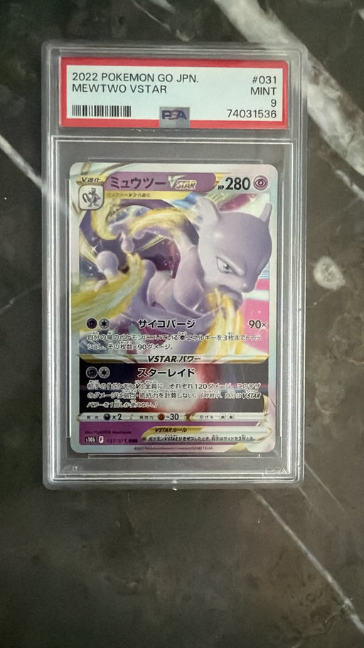 A graded 2022 Pokémon GO JPN Mewtwo V-Star trading card, PSA 9 Mint, sealed in a clear plastic PSA holder and placed on a dark marble surface.